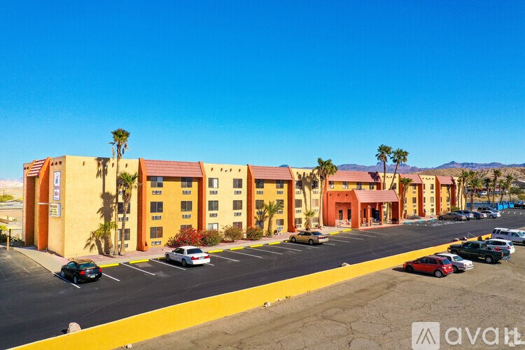A parking lot in front of a building with palm trees.