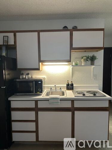 A kitchen with white cabinets and a black refrigerator.