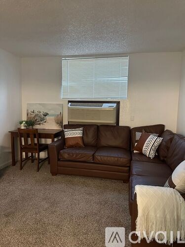 A brown leather couch with a white throw blanket on it.