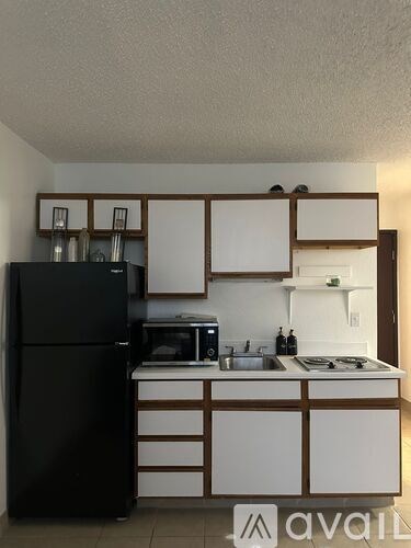 A kitchen with a black refrigerator and white countertops.