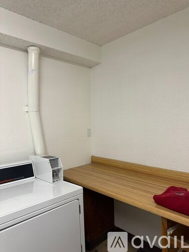 A white washing machine sits next to a wooden table with a red object on it.