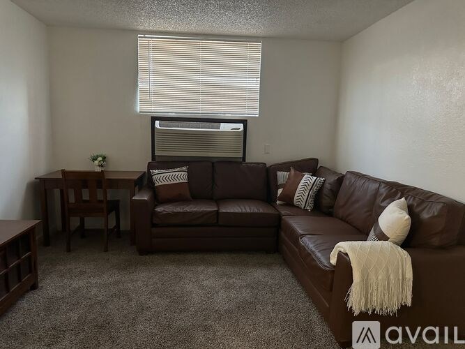 A living room with a brown leather couch and a small table.