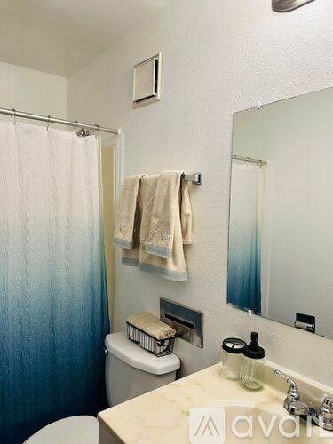 A bathroom with a toilet, sink, mirror, and towel.