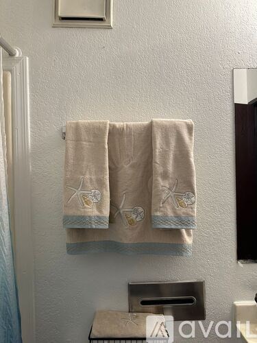 Two towels with starfish designs are hanging on a towel rack.