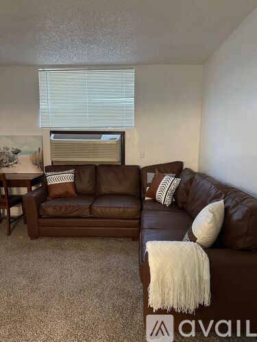 A living room with a brown couch and a white throw blanket.