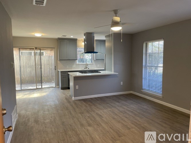 A spacious kitchen and living room with wooden flooring and a ceiling fan.