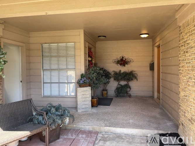 A patio with a bench, plants, and a door.