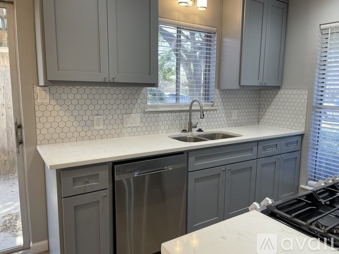 A kitchen with a white countertop and grey cabinets.