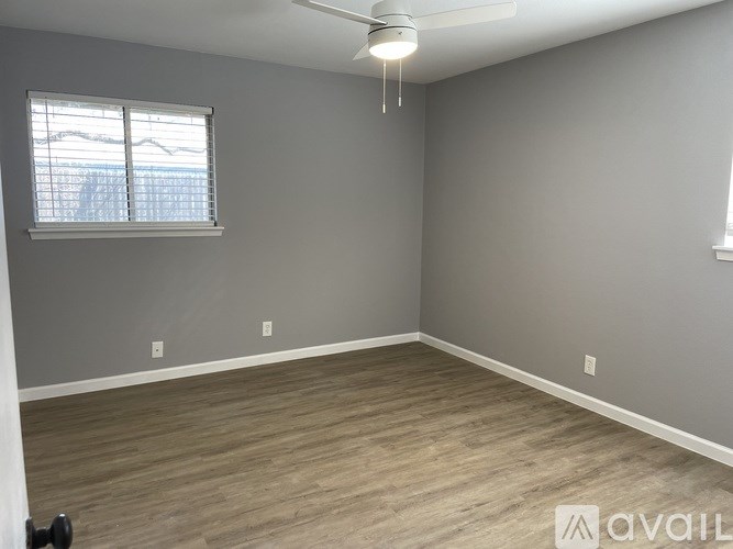 A room with a ceiling fan and a window with blinds.