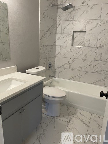 A white toilet sits next to a white sink in a marble bathroom.