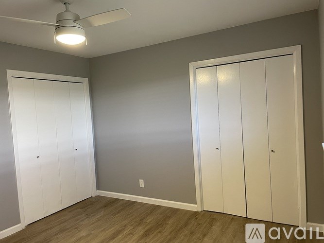 A room with a ceiling fan and three white doors.