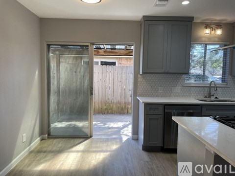 A kitchen with a white counter top and a glass door leading outside.