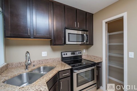 A kitchen with brown cabinets and a black stove top oven.