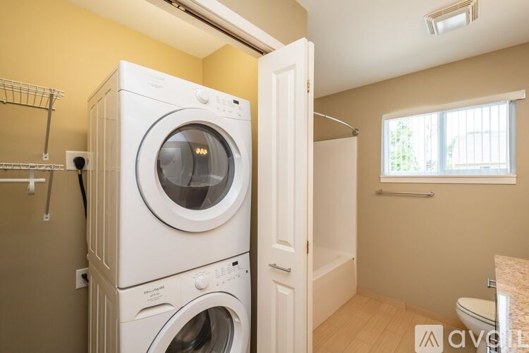 A white washing machine and dryer stacked on top of each other in a small laundry room.