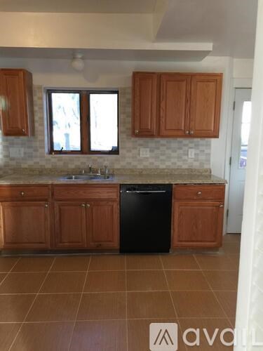A kitchen with brown cabinets and a black dishwasher.