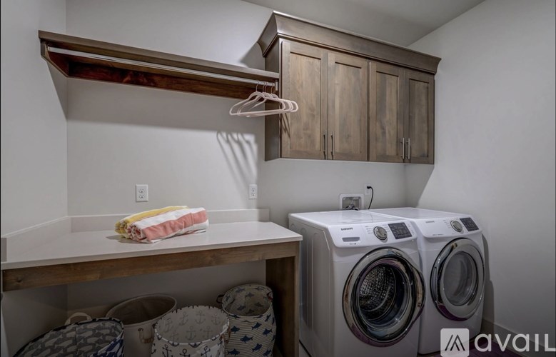 A laundry room with a washer and dryer, a shelf, and a hanging clothes rack.