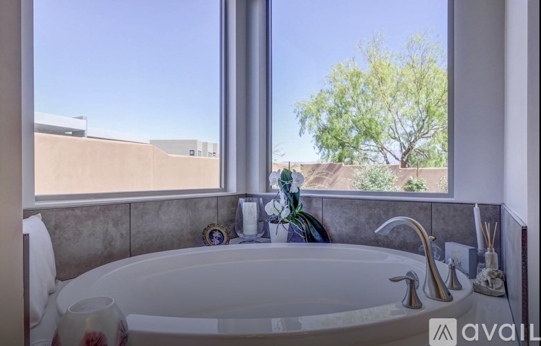 A bathroom with a tub and a window overlooking a tree.