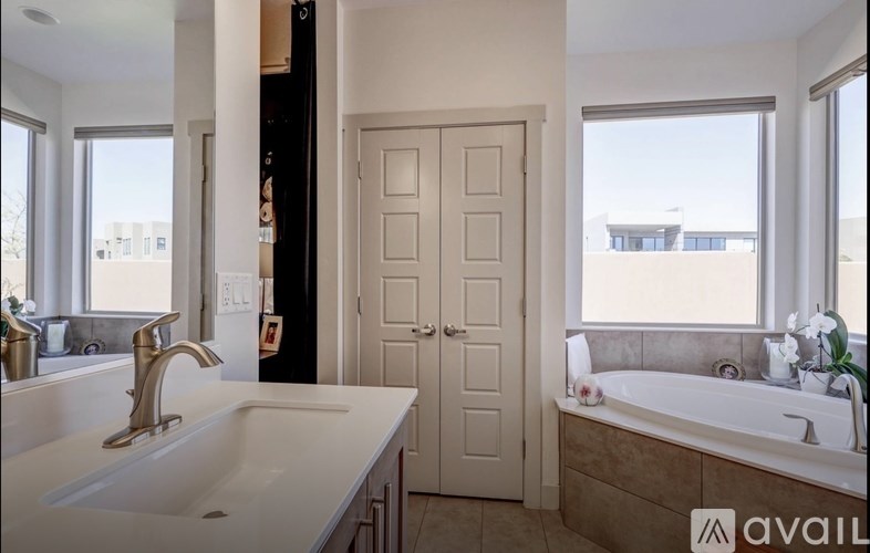 A bathroom with a sink, tub, and window.