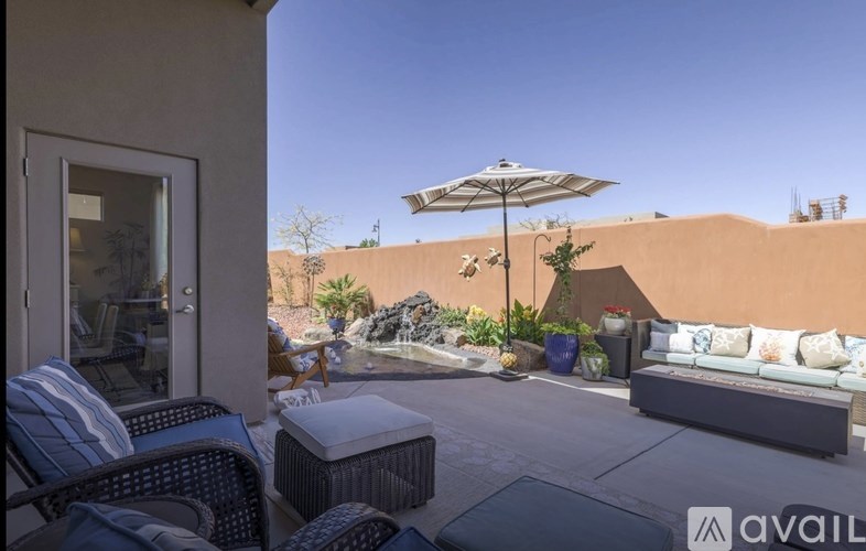 A patio with a couch, chairs, and a table with a white umbrella.