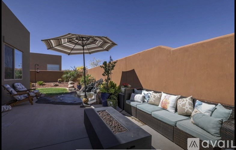 A patio with a couch, table, and umbrella.