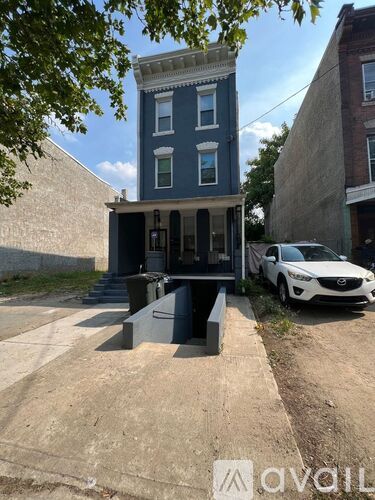 A two-story blue building with a white car parked in front.