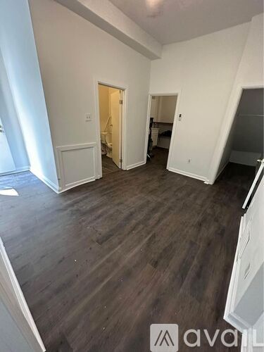 A spacious room with wooden flooring and white walls.