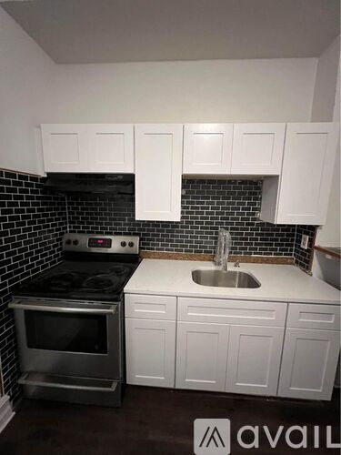 A kitchen with white cabinets and a black tile backsplash.