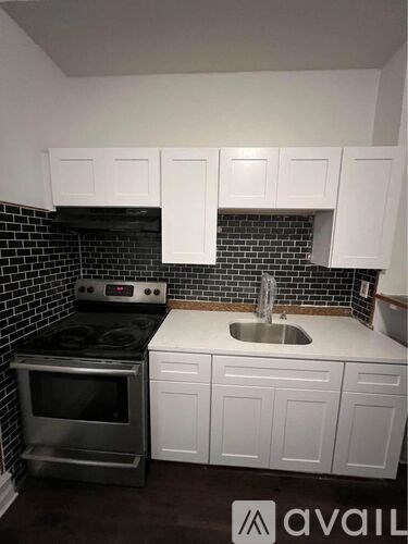 A kitchen with white cabinets and a black tile backsplash.