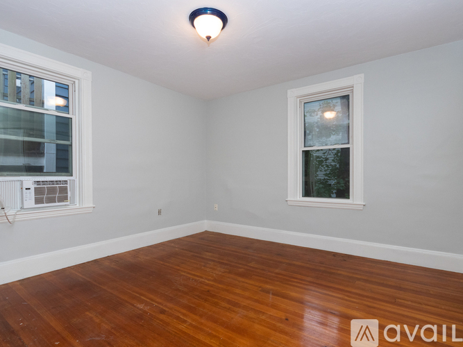 A room with wooden floors and two windows.