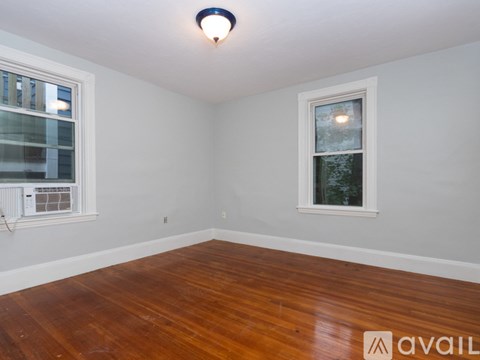 A room with wooden floors and two windows.