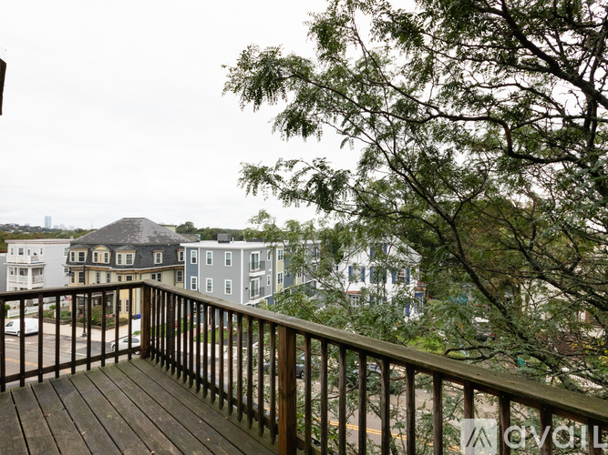 A balcony with a railing and a tree in front of apartment buildings.