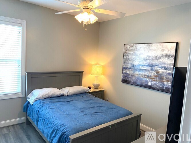 A bedroom with a blue bedspread and a ceiling fan.