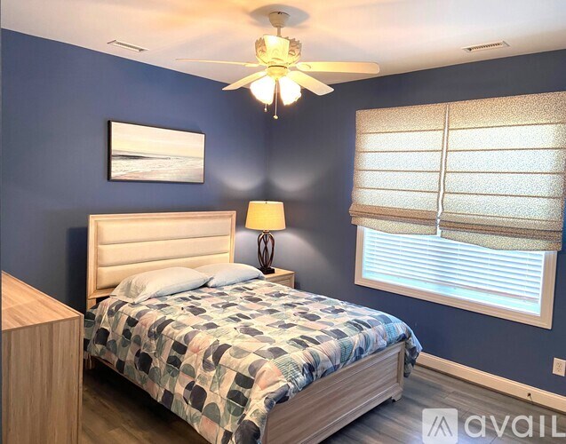 A bedroom with a bed, a ceiling fan, and a window with blinds.
