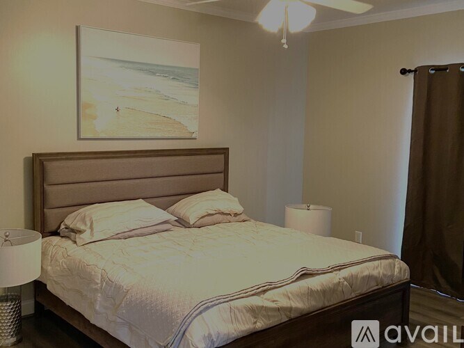 A bedroom with a bed, lamp, and a painting on the wall.