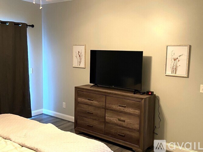 A TV is on a wooden stand in a bedroom.