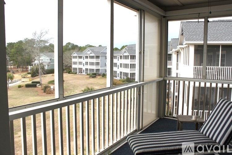 A balcony with a striped chair and a view of apartment buildings.