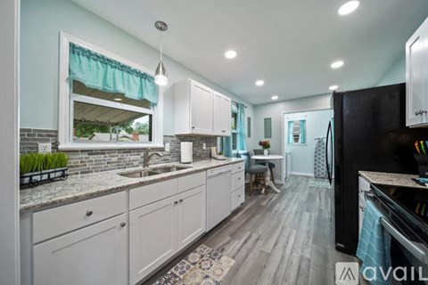 A kitchen with white cabinets and a black refrigerator.