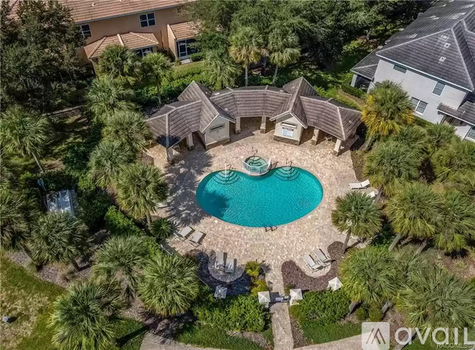 A bird's eye view of a house with a pool surrounded by palm trees.