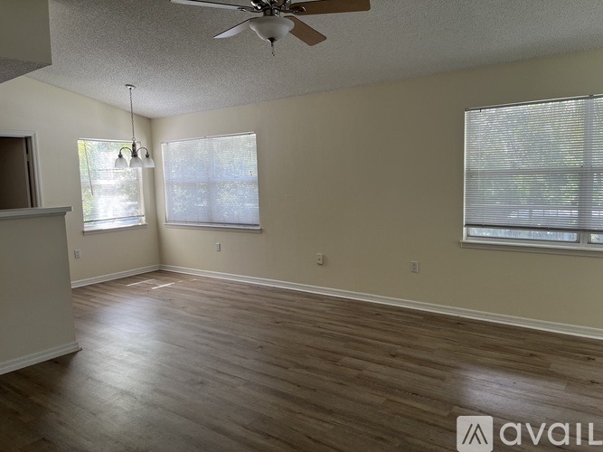 A room with a ceiling fan and two windows.