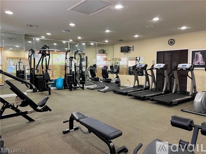 A gym with a variety of equipment including treadmills, weights, and exercise machines.