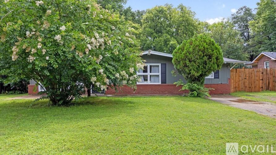 A house with a garden and a tree with white flowers in front of it.