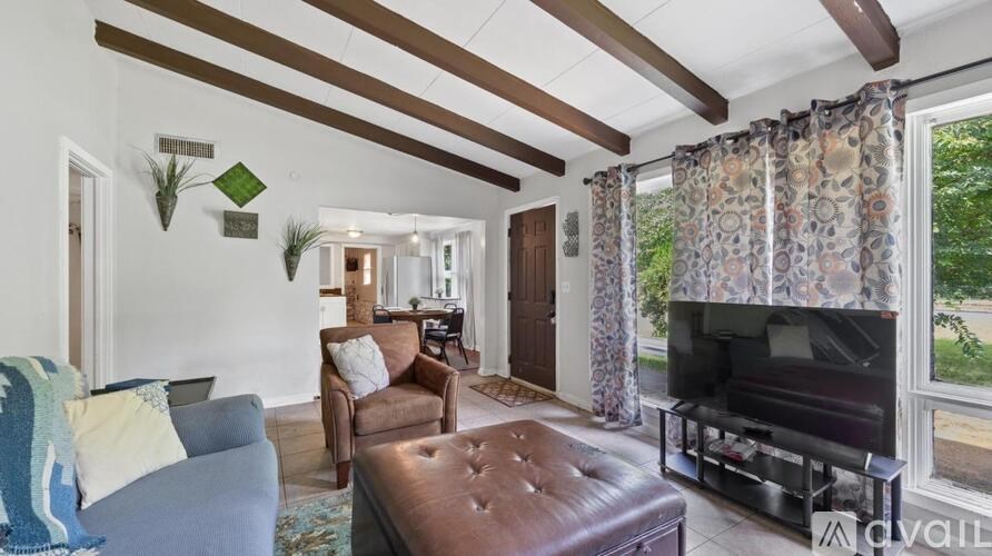 A living room with a brown leather ottoman and a blue couch.