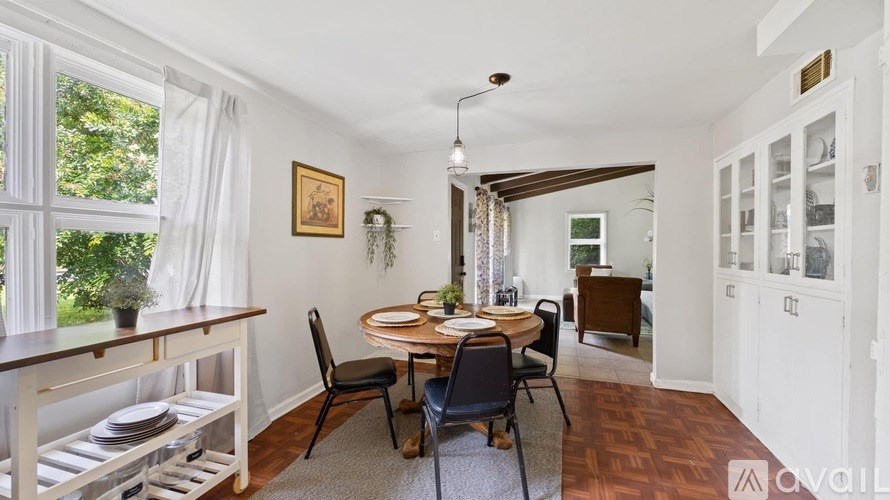 A dining room with a table set for four and a window with curtains.