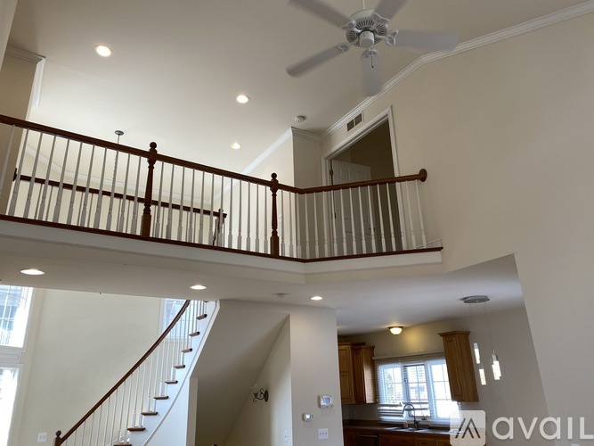 A well-lit, spacious interior of a house with a staircase and a balcony.
