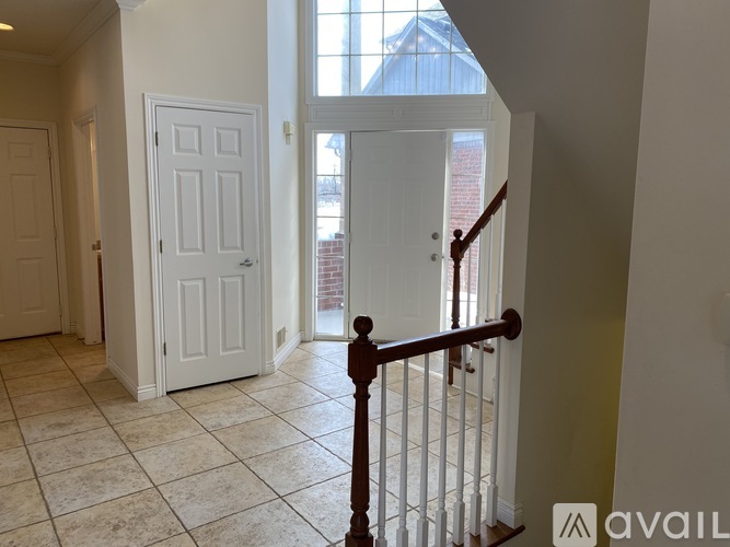 A room with a white door and a wooden railing.
