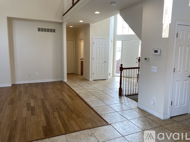 A spacious living room with hardwood floors and a staircase leading to another room.