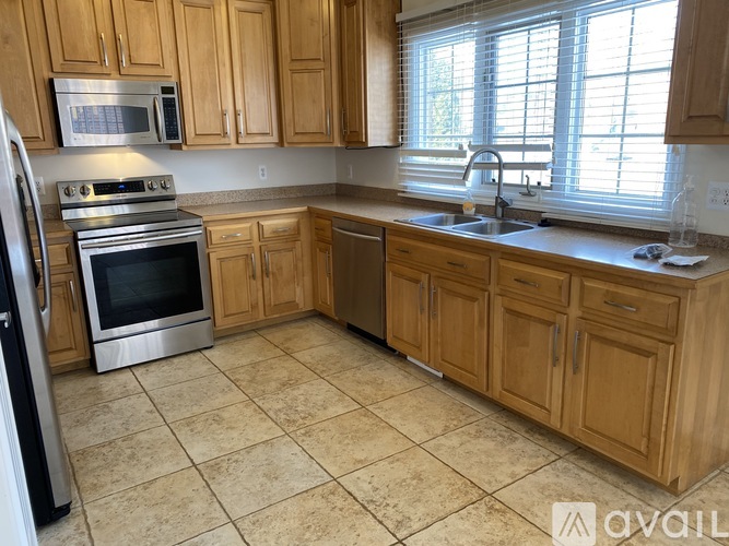 A kitchen with wooden cabinets and a black refrigerator.