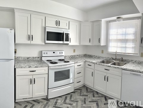 A kitchen with white cabinets and appliances.