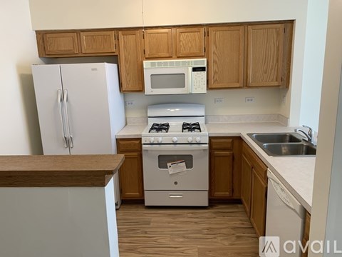 A kitchen with a white fridge, a white stove, a white microwave, and wooden cabinets.