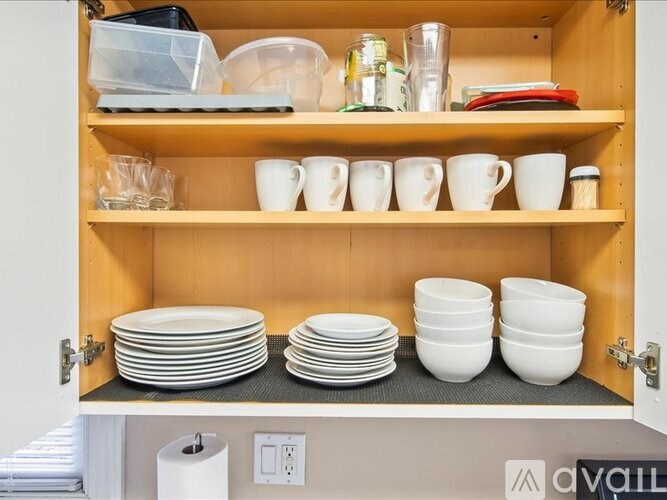 A kitchen cabinet with plates and cups on the shelves.
